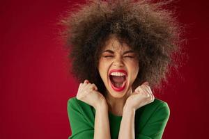 Beautiful fashionable girl with curly hair grimace posing emotion red background unaltered photo