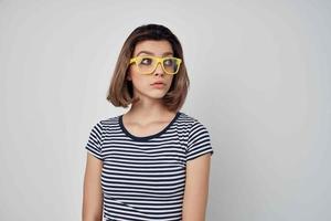 woman wearing yellow glasses striped t-shirt cropped view light background photo