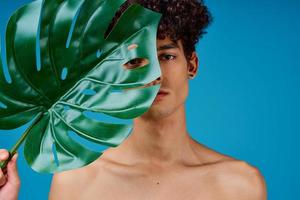 handsome man with curly hair naked shoulders green leaf clear skin photo