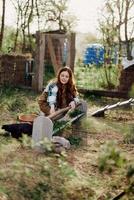 un mujer vierte comida dentro un pájaro alimentador mientras sentado en un pollo bolígrafo en el campo en un verano día en el luz de sol. el concepto de ecológico cuidado y orgánico agricultura foto