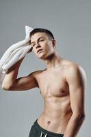 portrait of a sporty man with a pumped up body of a towel in his hands cropped view of a workout photo