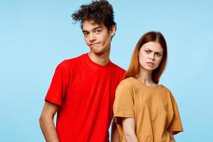 cheerful young couple in multicolored t-shirts communication studio blue background photo