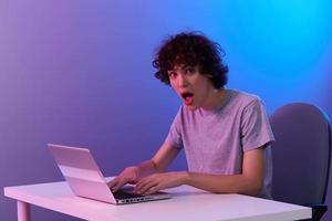 curly guy sitting at the table gaming laptop isolated background photo