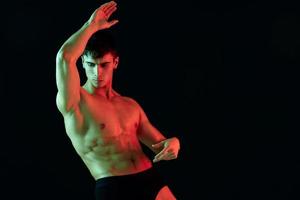 nude male athlete gesturing with his hands on a black background photo