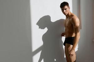 man athlete muscular body black panties in light background photo