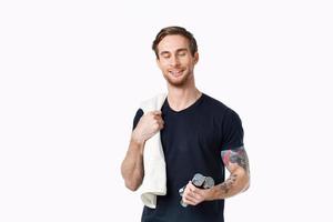 guy with a towel and dumbbells in his hand on a light background sports fitness bodybuilder photo