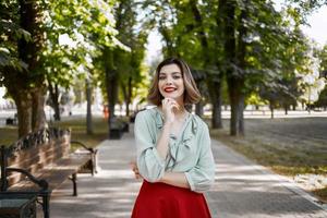 bonito mujer en rojo falda en el parque caminar estilo de vida Fresco aire foto