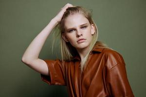 Stylish offer. Headshot portrait of beautiful blonde female model looks at camera posing isolated on over green olive wall photo