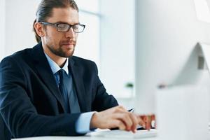 business man in a suit sitting at his desk tired in front of a computer photo