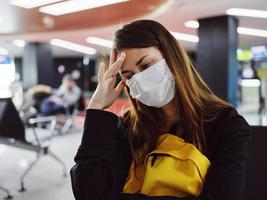 mujer participación su cabeza vistiendo médico máscara aeropuerto esperando pasajero foto