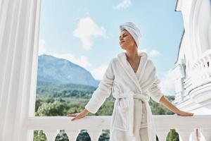 mujer en un blanco túnica en el balcón poco en verde naturaleza montaña ver foto