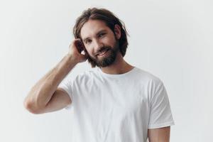 retrato de un alegre hombre con un negro grueso barba y largo pelo con un tipo sonrisa en un blanco camiseta en un blanco aislado antecedentes foto