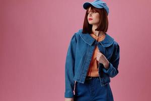 Pretty young female in a cap and denim jacket posing studio model unaltered photo