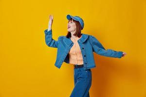 Portrait of a charming lady in a cap and denim jacket posing yellow background unaltered photo