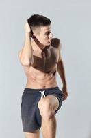 athlete in shorts doing exercise leaning forward on gray background cropped view photo