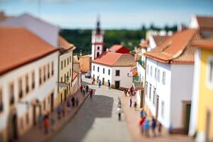 City life with living building facades and people walking at street, aerial view. Urban infrastructure. Model of city street in miniature, tilt shift. Created with Generative AI photo