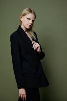 An attractive cool professional model holds a jacket by the lapel collar and poses on a green olive background in the studio. Cool banner for brands photo