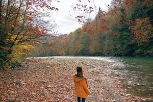 woman in a yellow jacket near the river mountains nature walk photo