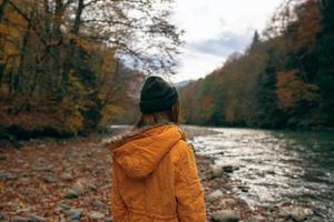 mujer caminando a lo largo el río caído hojas otoño viaje foto