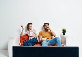 Watching TV married couple man and woman on the couch and a flower in a pot photo