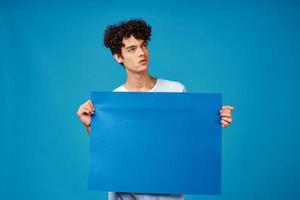 Cheerful man with curly hair blue poster close-up photo