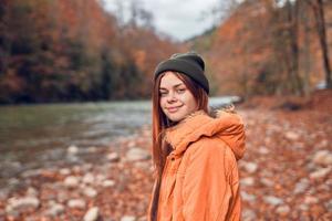 bonito mujer en otoño ropa en el bosque río caído hojas foto