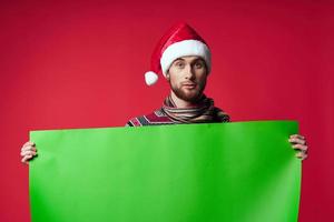Cheerful man in a santa hat holding a banner holiday isolated background photo