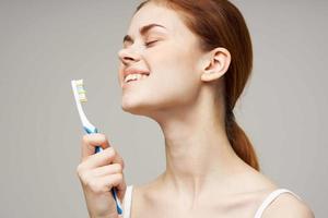 bonito mujer con un cepillo de dientes en mano Mañana higiene ligero antecedentes foto