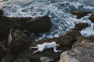 attractive woman with long hair in a white dress lying on a stone in a white dress unaltered photo