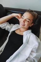 A woman lying on the couch with her glasses on and wriggling photo