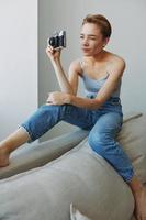 Woman photographer shooting in studio on old film camera at home on couch portrait, white background, free copy space, freelance photographer photo