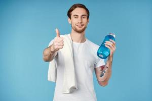 sporty man showing thumb up water bottle towel on shoulder cropped view blue background photo