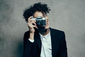 curly-haired man in a classic suit looks at the camera in his hand studio hobby photo