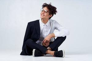 emotional guy in a classic suit sits on the floor in a bright room glasses on the face portrait model photo