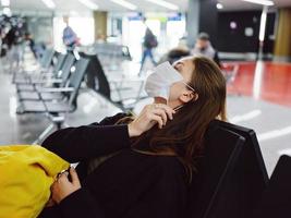 woman wearing a medical mask tilted her head back sitting at the airport waiting photo