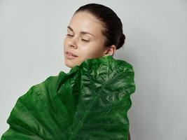 bonito mujer limpiar piel cosmetología verde palma hoja cerrado ojos foto