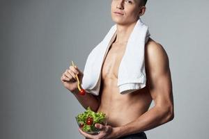 Deportes chico blanco toalla en su espalda inflado torso plato ensalada vitaminas foto