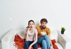 Couple in love with popcorn and watching TV while on the couch indoors photo