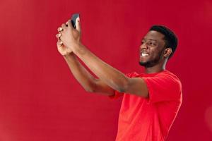 Cheerful man of african appearance holding phone above his head communication isolated background photo