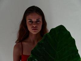 pretty woman serious expression red swimsuit palm leaf close-up photo