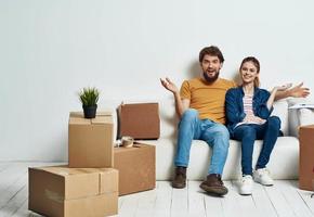 Married couple on a white sofa in the room interior with boxes of communication things photo