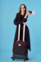 Woman in black coat suitcase sunglasses vacation blue background photo