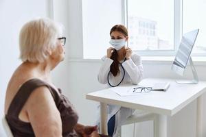 mayor mujer vistiendo un médico máscara comunica con el médico médico oficina foto