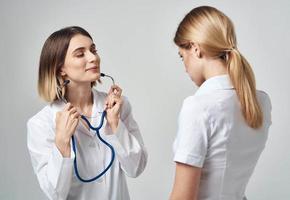 A nurse with a stethoscope and a patient on a light background photo