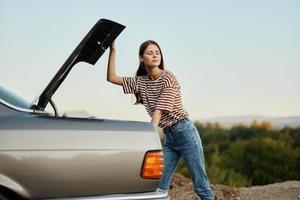 The woman driver of the car opened the trunk with looks. Car breakdown while traveling on the road. Car and woman repair concept photo