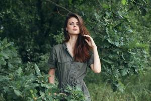 mujer en el bosque sostiene su pelo y mira adelante foto