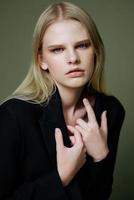 A close portrait of a blonde crossing her arms on her chest holding a jacket by the collar photo