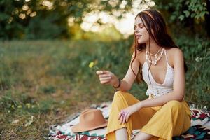 niña vestido como un hippie eco relajante en el parque, sentado en un cobija en el atardecer, relajado estilo de vida foto