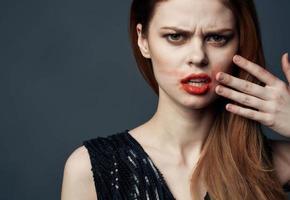 Woman in black dress touching face with hands and lipstick stress irritability photo
