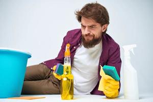 A man lies on the floor with a bucket of detergents providing services light background photo